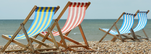 Beach chairs lined up on sandy beach