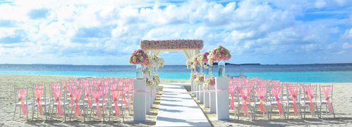 Beachside wedding setup with floral arch and chairs